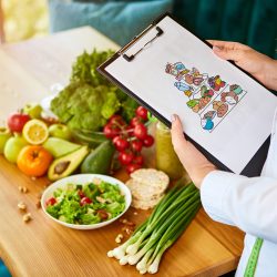 Holding schematic meal plan for diet with various healthy products on the background. Weight loss and right nutrition concept. Eating food pyramid Holding schematic meal plan for diet with various healthy products on the background. Weight loss and right nutrition concept. Eating food pyramid